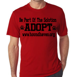This picture is of a man wearing a red t-shirt. In black lettering on the t-shirt it reads, "Be Part Of The Solution". The next line, in very large block letters it reads, "ADOPT" on either side of the word "adopt" is a dog paw. The third row says, "www.houndhaven.org".