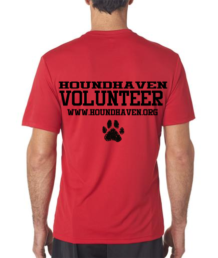This is a picture of man standing with his back to you. He has a red t-shirt on with 3 rows of black lettering. The first row in bold capital letters says, "HOUNDHAVEN". The second row in larger bold capital letters says, "VOLUNTEER". The third row, in small capital letters says, "WWW.HOUNDHAVEN.ORG". There is paw print in the center of the shirt under the lettering.