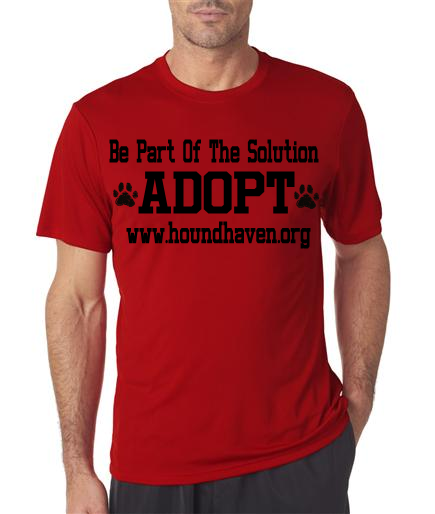 This picture is of a man wearing a red t-shirt. In black lettering on the t-shirt it reads, "Be Part Of The Solution". The next line, in very large block letters it reads, "ADOPT" on either side of the word "adopt" is a dog paw. The third row says, "www.houndhaven.org".